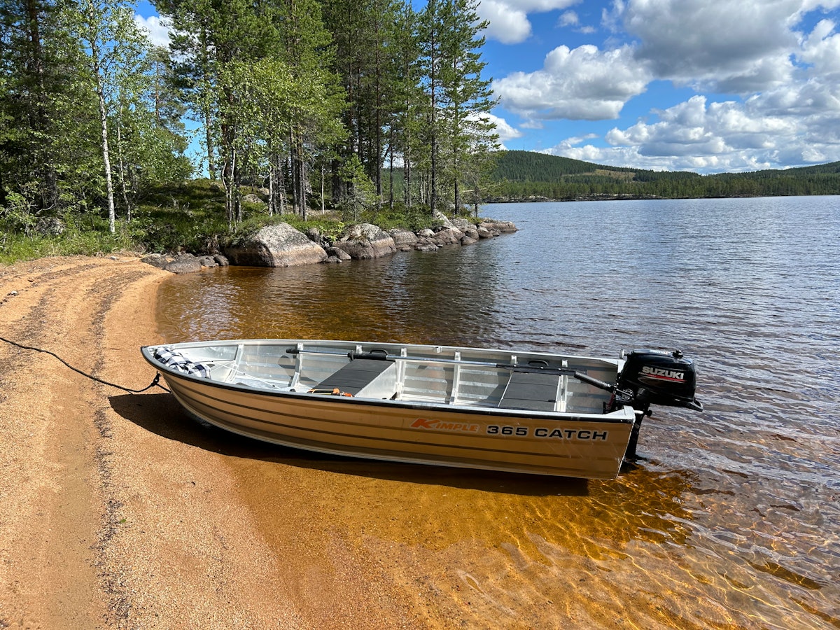 Alumiinivene moottorilla rannassa.